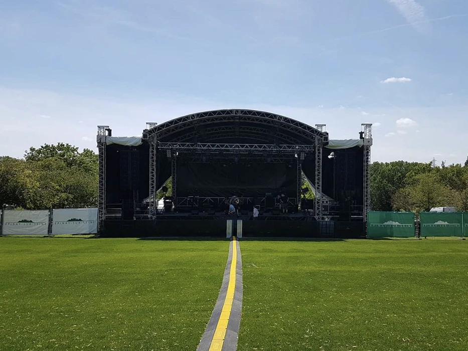 Scène extérieure d'une grande structure de concert temporaire installée sur pelouse