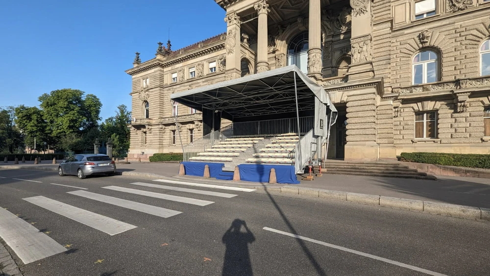 Scène extérieure devant bâtiment historique en pierre avec colonnes néoclassiques
