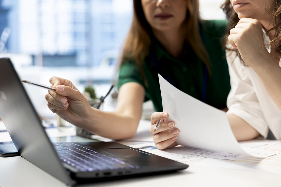 Conf&eacute;rencier en costume sombre pr&eacute;sentant devant un large &eacute;cran de projection bleu dans une salle de conf&eacute;rence moderne