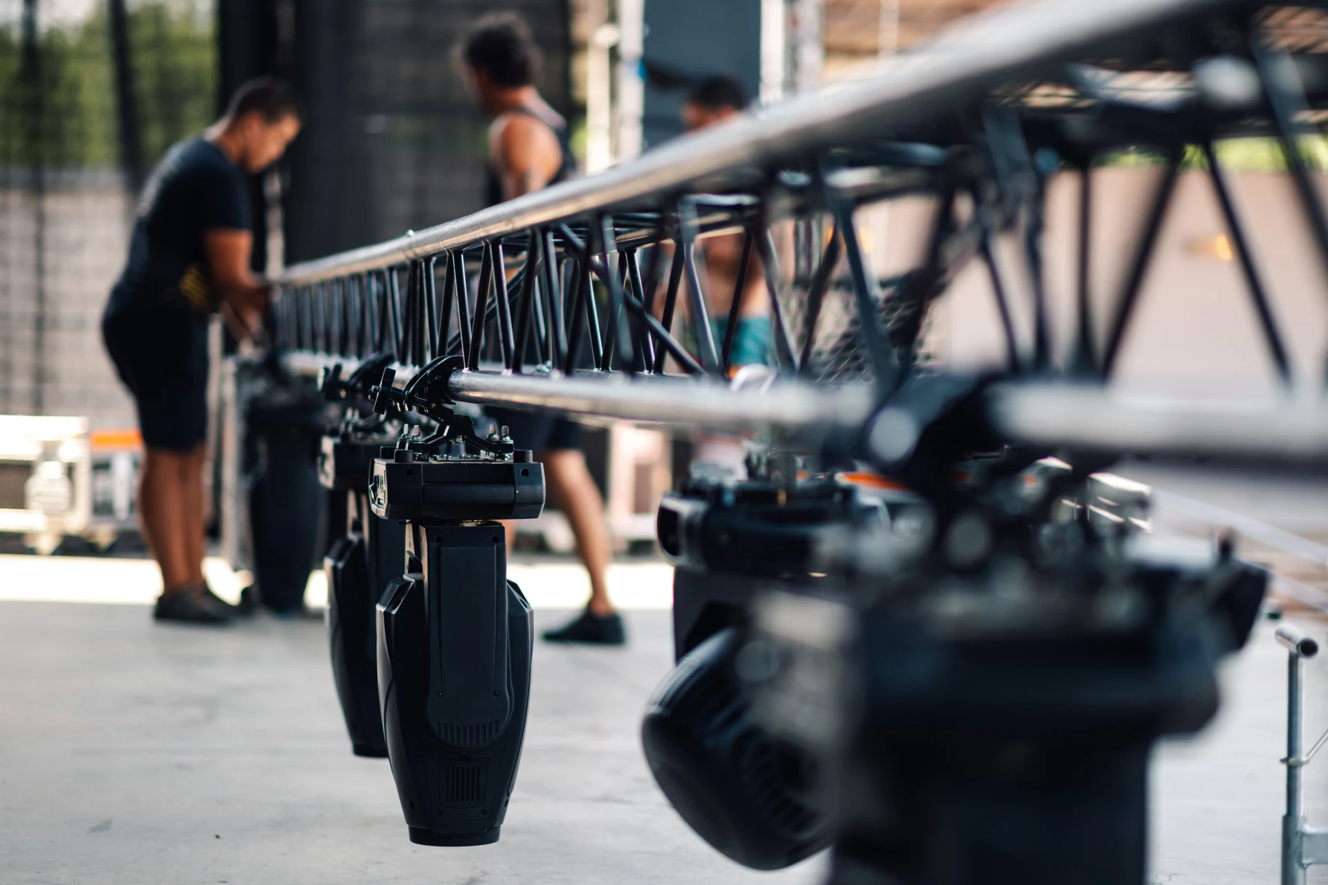 Homme en costume sombre avec oreillette de sécurité surveillant un événement professionnel dans un hall moderne avec éclairage bleu et participants en arrière-plan