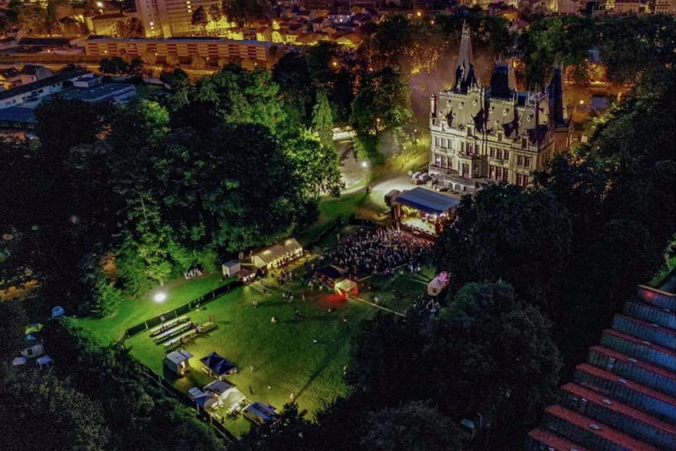 Scène extérieure de montage d'une scène de concert avec techniciens installant équipements audio et instruments