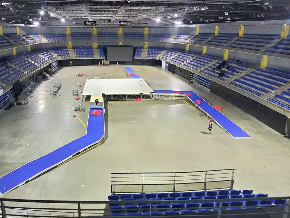 Scène extérieure de montage d'une scène de concert avec techniciens installant équipements audio et instruments