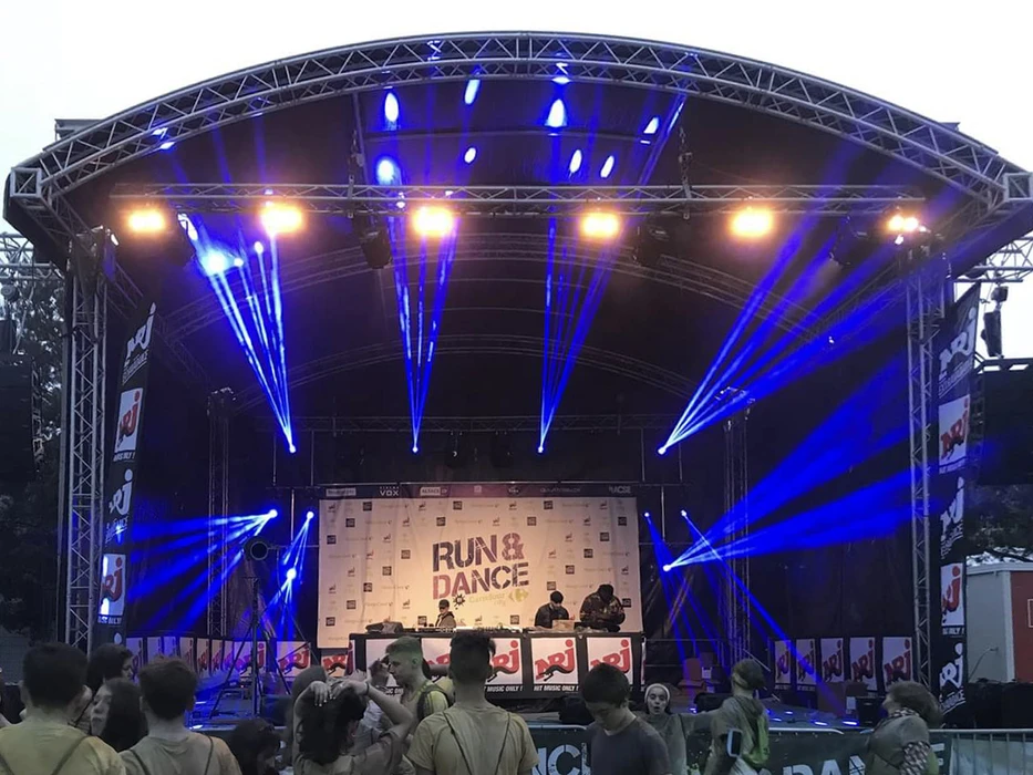 Scène extérieure de festival musical avec foule nombreuse devant une scène couverte