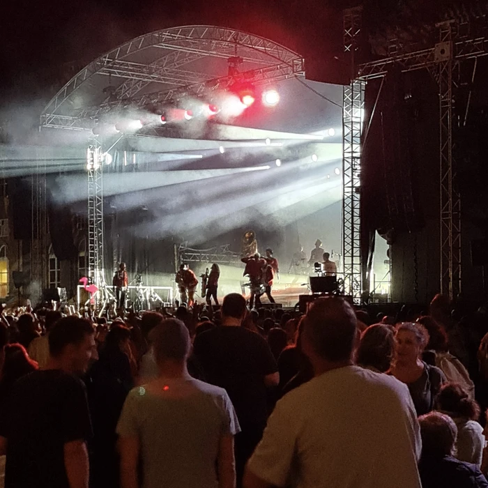 Scène extérieure de festival musical avec foule nombreuse devant une scène couverte
