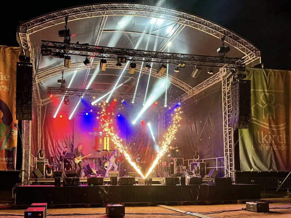 Scène extérieure de festival musical avec foule nombreuse devant une scène couverte