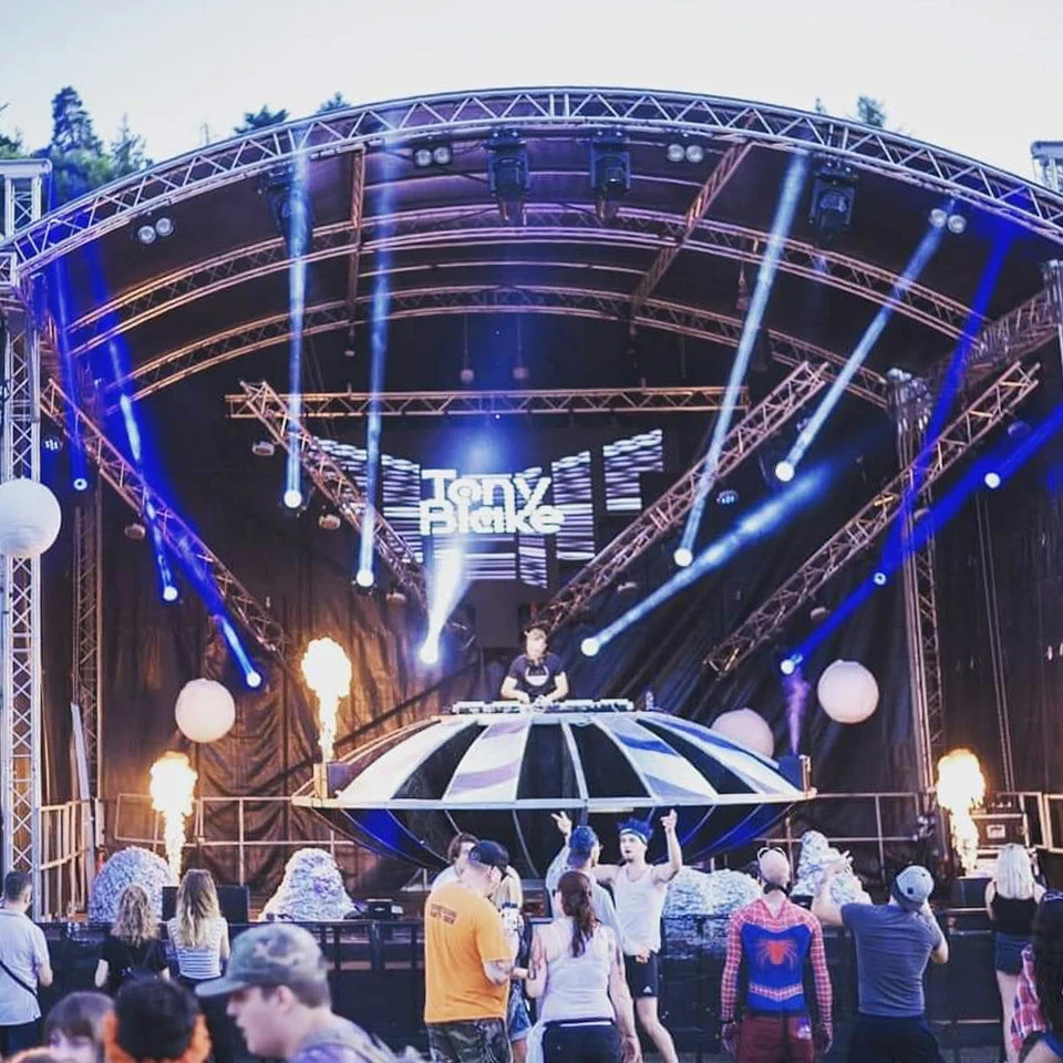 Scène extérieure de festival musical avec foule nombreuse devant une scène couverte