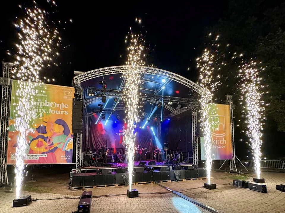 Scène de concert vide avec éclairage professionnel bleu, projecteurs à tête mobile positionnés sur la scène, faisceaux lumineux croisés créant une atmosphère spectaculaire dans une salle de spectacle