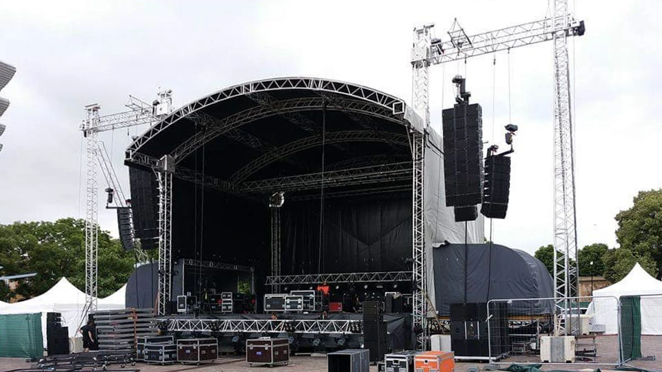 Scène de concert en préparation sous chapiteau avec techniciens effectuant le montage