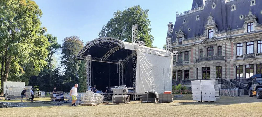 Scène de concert en préparation sous chapiteau avec techniciens effectuant le montage