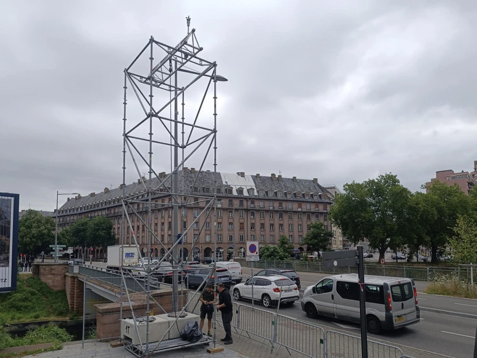 Scène de concert en extérieur nocturne avec musiciens sur scène sous structure métallique triangulée