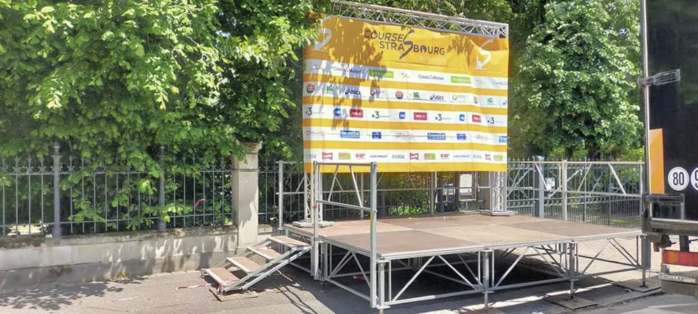 Scène extérieure d'un festival avec une scène principale vide sous ciel bleu nuageux