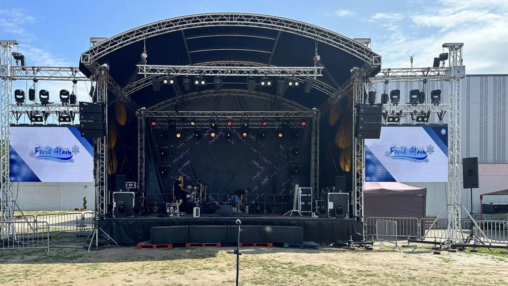 Concert en extérieur avec scène professionnelle, musiciens en performance devant public nombreux