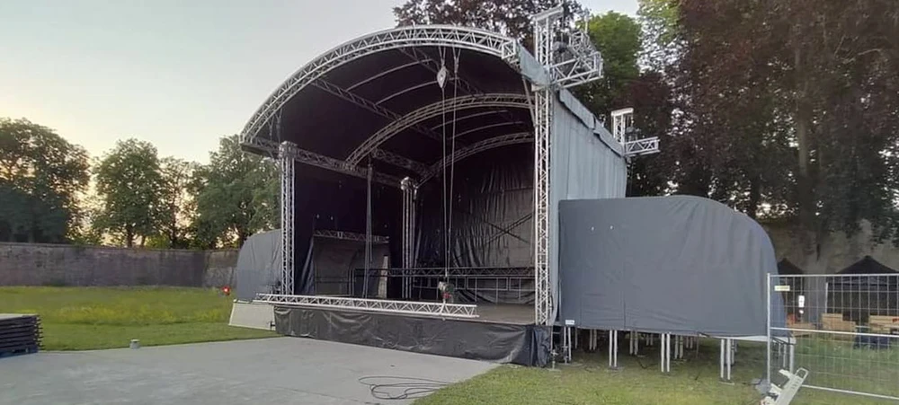 Scène extérieure d'un festival avec une scène principale vide sous ciel bleu nuageux
