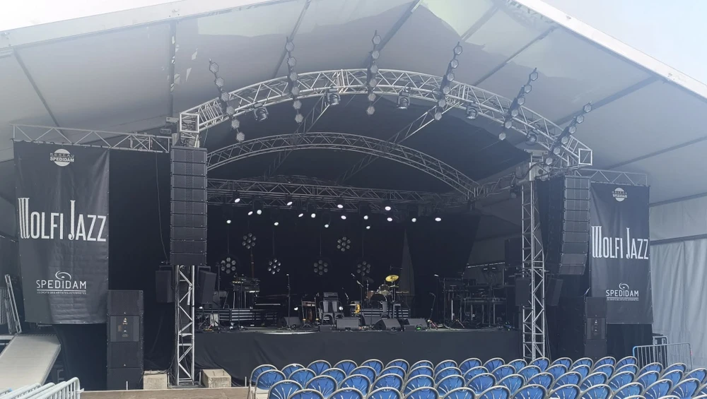 Concert en extérieur avec scène professionnelle, musiciens en performance devant public nombreux