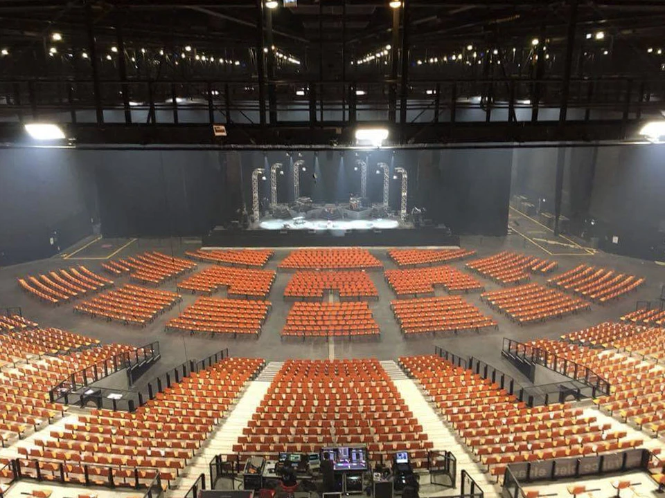 Scène extérieure de montage d'une scène de concert avec techniciens installant équipements audio et instruments